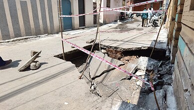 Road collapse on Hussaini Kothi Road due to stormwater drain failure, causing a large sinkhole.