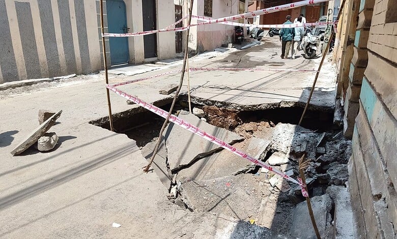 Road collapse on Hussaini Kothi Road due to stormwater drain failure, causing a large sinkhole.