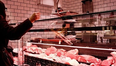 Customer selecting fresh meat at Hyderabad meat shop with glass display case.