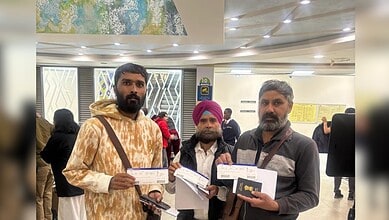Three Indian nationals hold documents at an airport after being repatriated from Kenya.