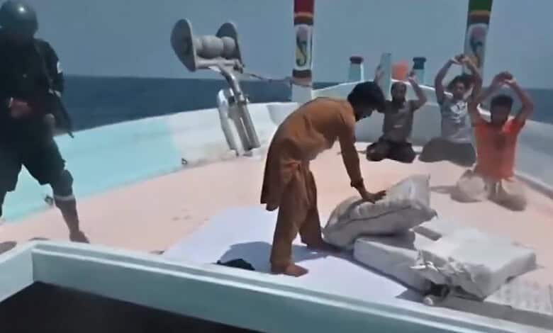 Authorities inspect large packages of seized drugs on a boat in the Arabian Sea with personnel and onlook.