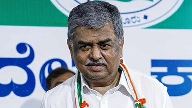 Hariprasad speaking at a public event with a green and white background.