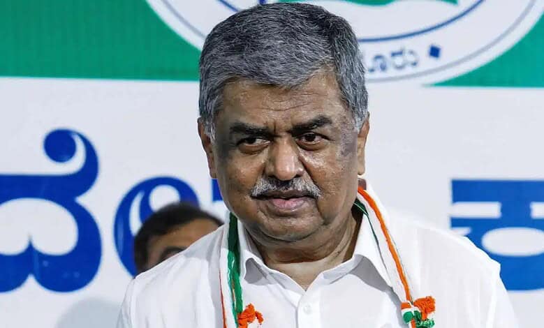 Hariprasad speaking at a public event with a green and white background.