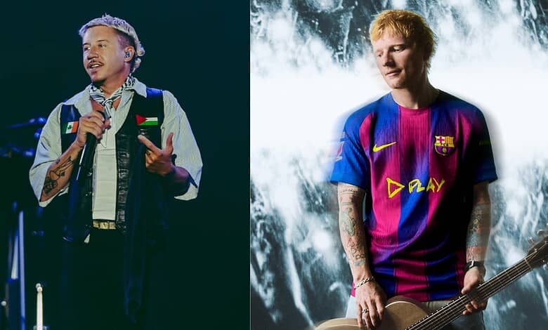 Rapper Macklemore performing on stage with a microphone, wearing a denim vest and patterned shirt.