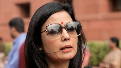 Mahua Moitra speaking at the UN, wearing glasses and a red bindi, with a serious expression.