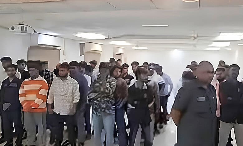 Crowd of police officers and civilians gathered in an indoor space during a public event.