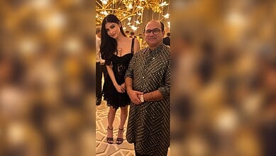 Mouni Roy seeking blessings from Rahat Fateh Ali Khan at an event with festive lighting.