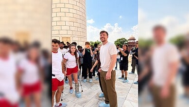 Group of tourists at Taj Mahal with a smiling man in white shirt in the centre.