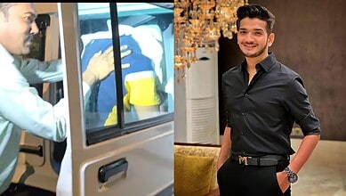 Man in black shirt smiling indoors, possibly at a social event or gathering.