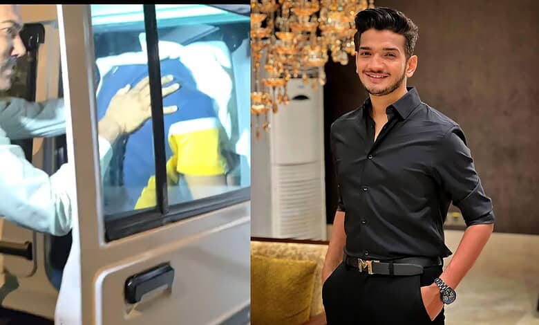 Man in black shirt smiling indoors, possibly at a social event or gathering.