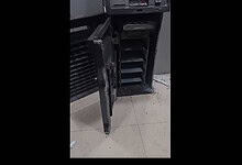 Damaged ATM machine with open cash compartment and debris on the floor.