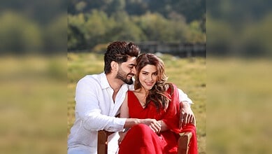 Nikki Tamboli and Arbaaz Patel in a romantic outdoor setting, smiling and holding hands.