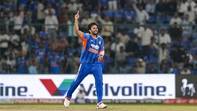 Indian cricket player celebrating on the field during a match in blue jersey.