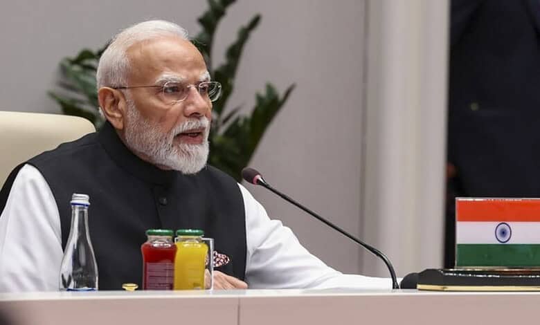 Indian Prime Minister Narendra Modi speaking at SCO summit with Indian flag on table.