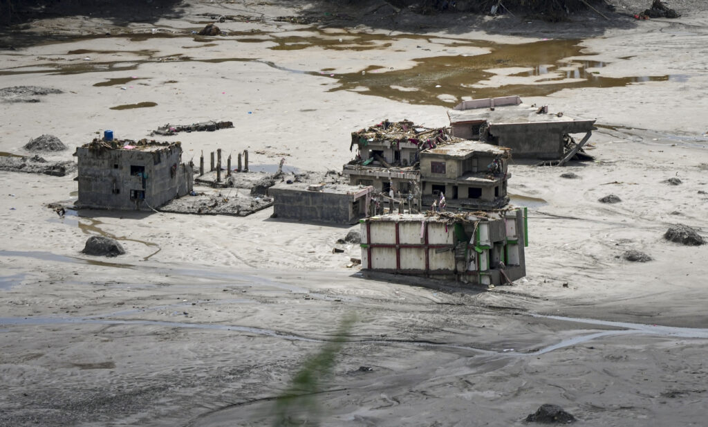 Flooded village with damaged buildings and muddy terrain in Nepal.