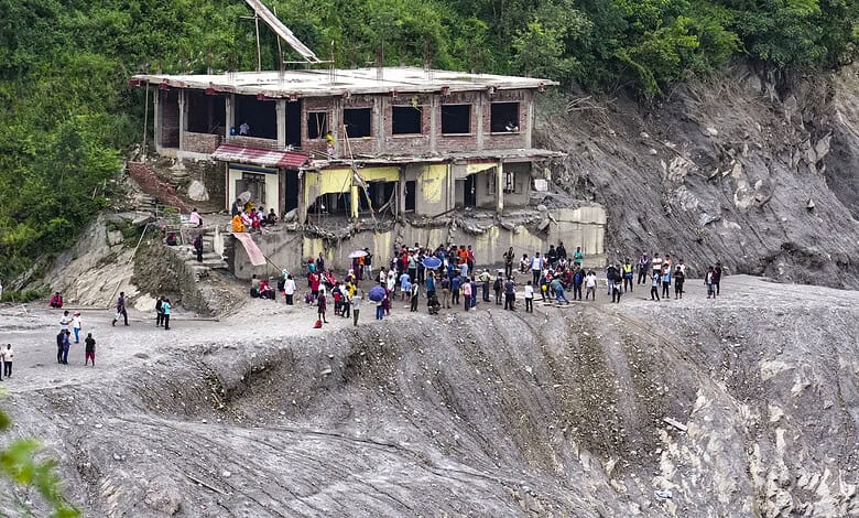 People gather near a damaged building on a landslide-affected hillside in Nepal.