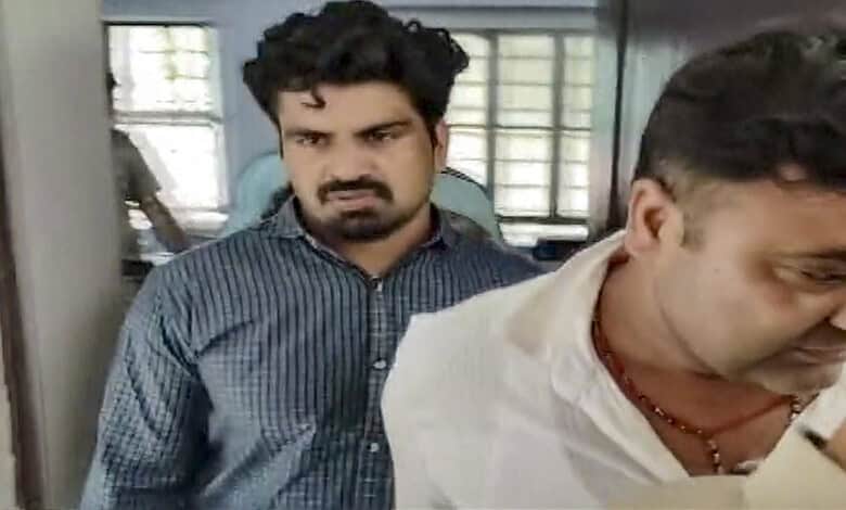 Man in white shirt and man in blue shirt in a room with windows and metal bars.