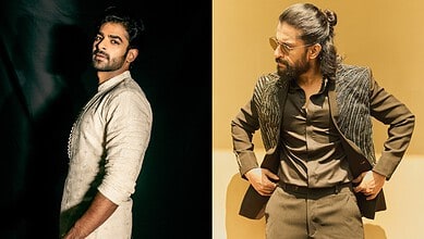Two men in stylish outfits, one with a beard and the other with glasses and a bun hairstyle.