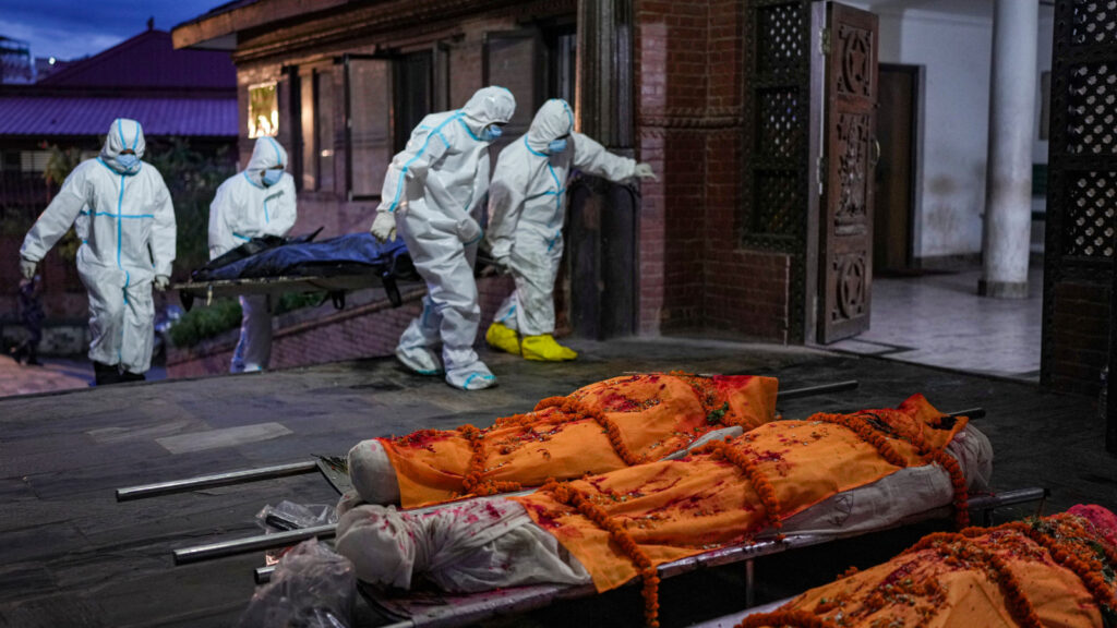 Personnel clad in PPE suits carry the body of a flood victim on a stretcher as wrapped bodies lie on stretchers outside the Pashupatinath Electric Crematorium, in Kathmandu, Nepal, Wednesday, Sept