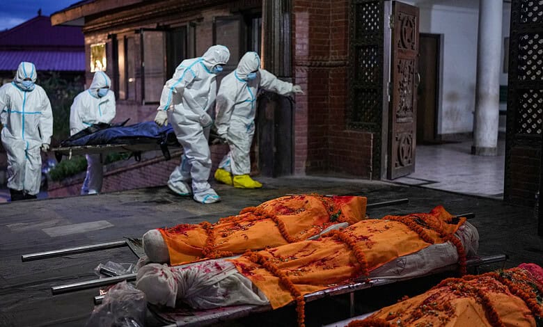 Personnel clad in PPE suits carry the body of a flood victim on a stretcher as wrapped bodies lie on stretchers outside the Pashupatinath Electric Crematorium, in Kathmandu, Nepal, Wednesday, Sept