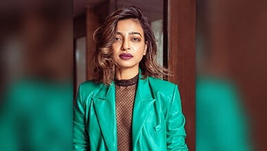 Radhika Apte in a teal blazer and black top, looking confidently at the camera.