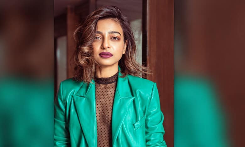 Radhika Apte in a teal blazer and black top, looking confidently at the camera.
