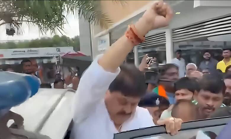 Protesters gather around a man raising his fist during a demonstration.