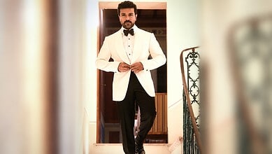 Man in white tuxedo with black bow tie standing at doorway, stylish and confident.