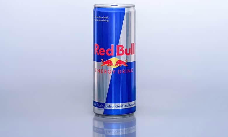 Close-up of a Red Bull energy drink can on a plain background.