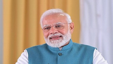 Indian Prime Minister Narendra Modi smiling in a blue kurta at a formal event.