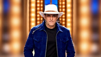 Salman Khan in a blue jacket and white hat on a brightly lit stage.