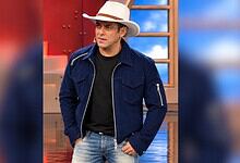 Salman Khan in a blue jacket and white hat on the Bigg Boss set.