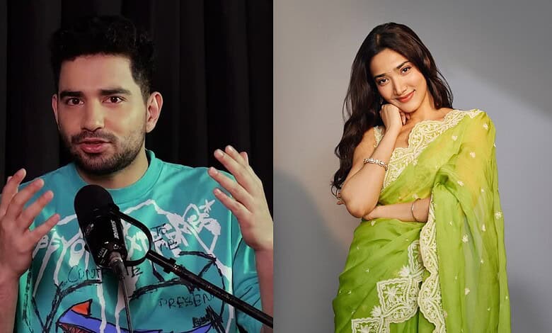 Comedian Samay Raina speaking at an event with a woman in a green saree smiling nearby.