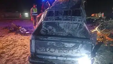 Burnt and damaged vehicle involved in a fatal road accident in Saudi Arabia at night.