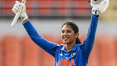 Smriti Mandhana celebrating with bat and helmet during a cricket match for India.