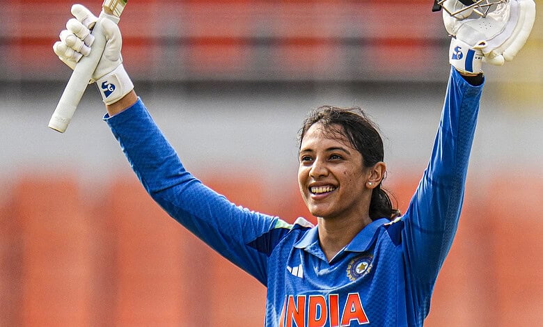Smriti Mandhana celebrating with bat and helmet during a cricket match for India.