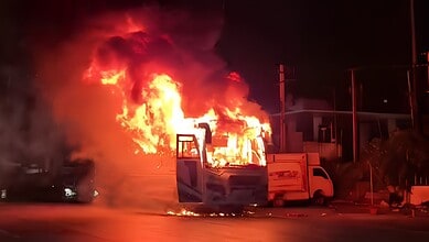 Bus on fire in Hyderabad with large flames and thick black smoke at night.