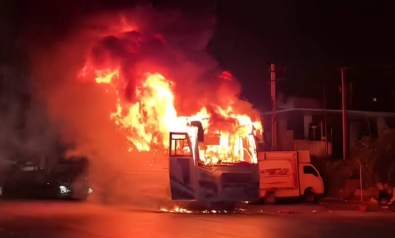 Bus on fire in Hyderabad with large flames and thick black smoke at night.