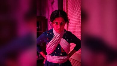 Taapsee Pannu in a traditional outfit with intense expression, pink lighting background.