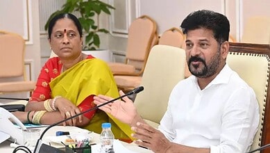 Konda Surekha speaking during a meeting with a woman in a yellow saree in the background.