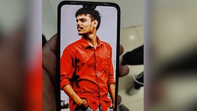 Young man in red shirt displayed on a smartphone screen.