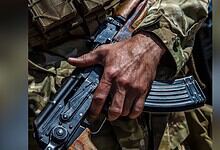 Close-up of a soldier's hand holding a rifle in camouflage uniform.