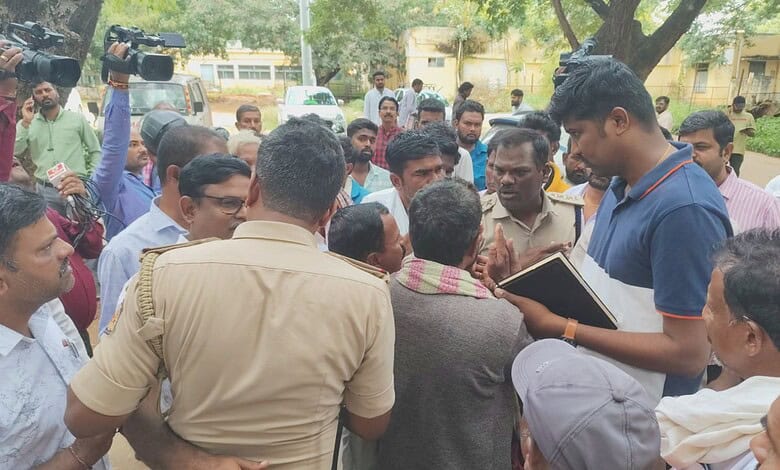 Group of people gathered outdoors, engaging in discussion, with a man taking notes in a notebook.