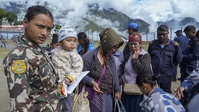 Nepalese stranded in China return home, women and children among crowd at border.
