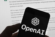 OpenAI logo displayed on a smartphone screen with a document in the background.