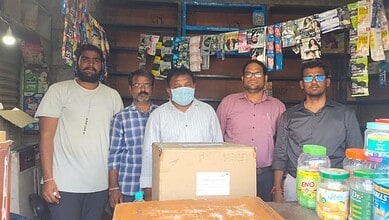 Group of five men standing in a shop with shelves of products behind them.