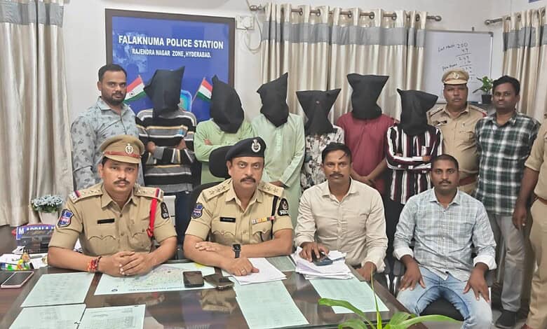 Seven individuals detained by police, with some suspects masked, in a police station in Hyderabad.