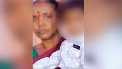 Woman with a red bindi holding a child at Nizamabad hospital, emotional scene.