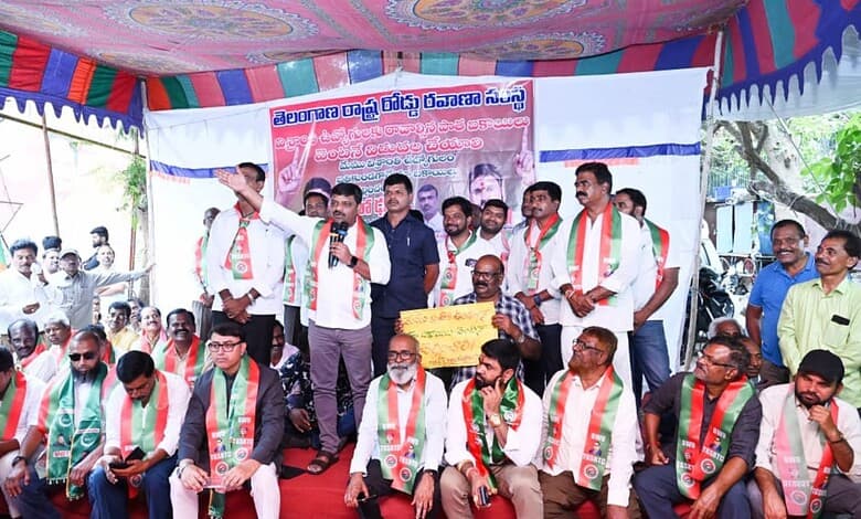 Ex-RTC employees protest in Hyderabad over unpaid dues, holding banners and speaking to crowd.