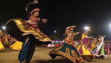 Women performing traditional Garba dance during Navratri festival at night.